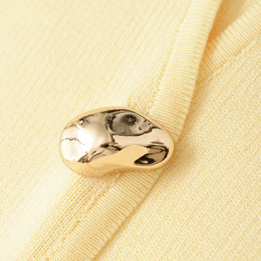 Pastellfärgad stickad kofta med V-ringning och guldfärgad knapp