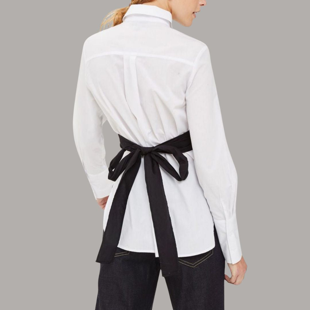 Vit skjorttopp med svart omlottdetalj och knytband i midjan för en modern silhuett