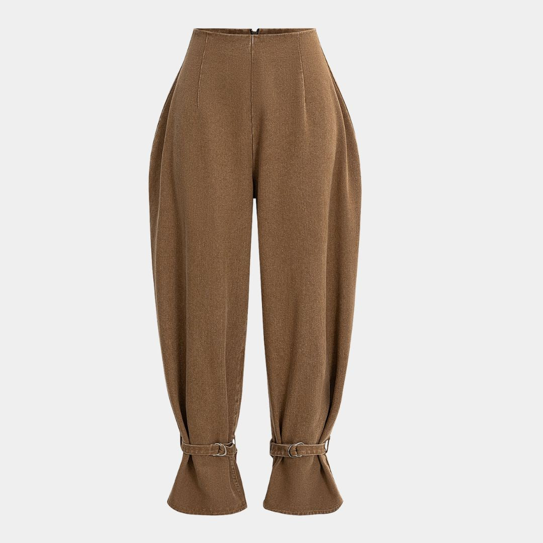 Bruna bomullsbyxor i denim med markerad höftvolym, formsydd midja och justerbara benslut med metallspännen