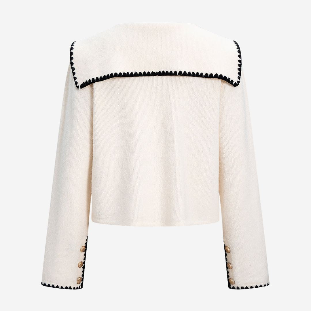 Vit stickad kofta med kontrastkant och dekorativa knappar