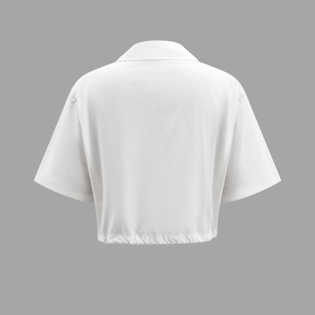 Vit kort skjortblus med stora fickor och dragsko i fållen