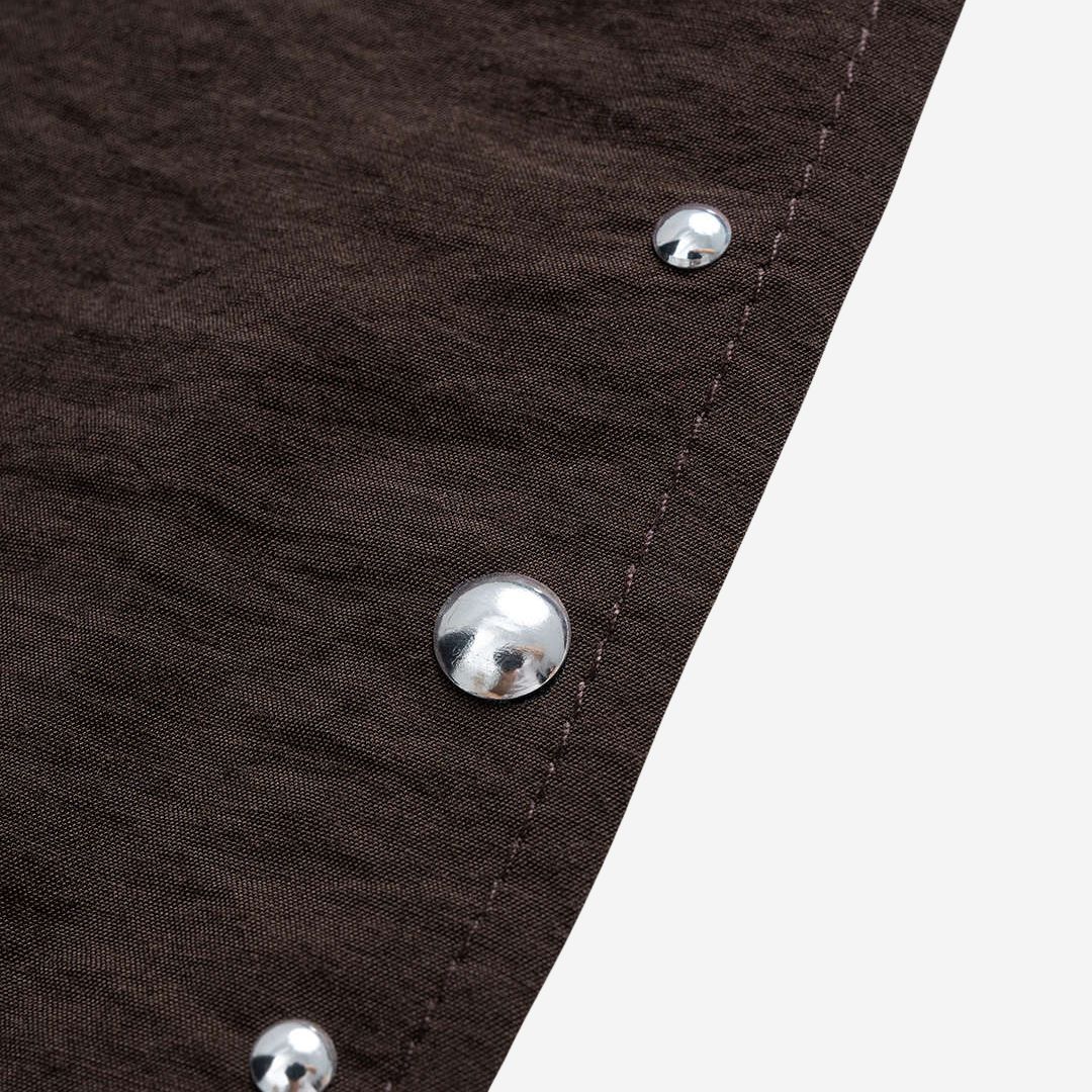 Mörkbrun asymmetrisk topp med halsbandseffekt och silverfärgade nitar