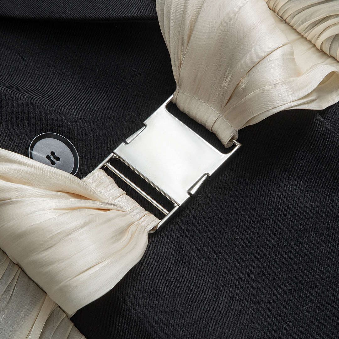 Svart ärmlös kavajväst med plisserade volanger och dekorativt metallspänne