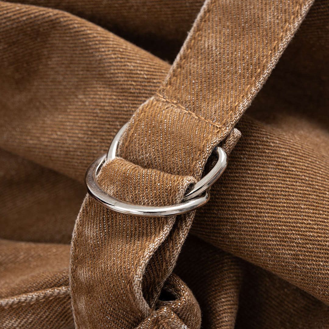 Bruna bomullsbyxor i denim med markerad höftvolym, formsydd midja och justerbara benslut med metallspännen