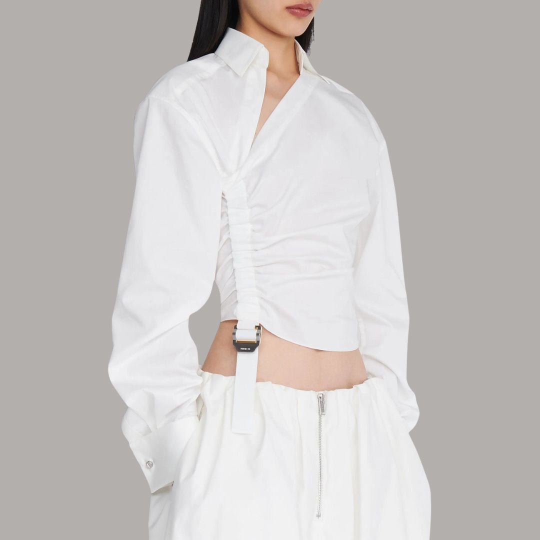 Vit asymmetrisk skjorttopp med markerad midja och industriell spänndetalj