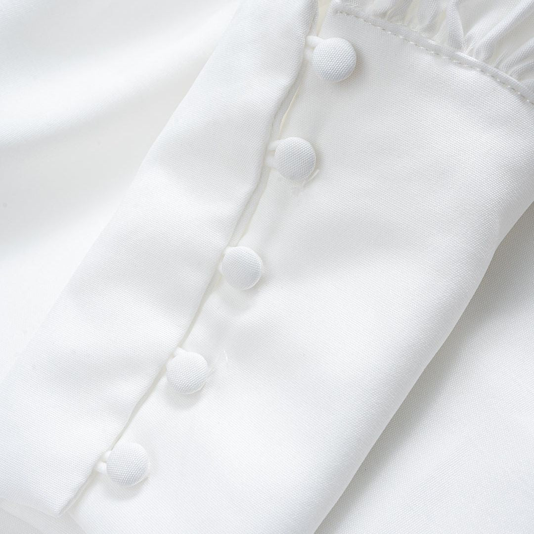 Vit blus med ståkrage täckta knappar och vida puffärmar