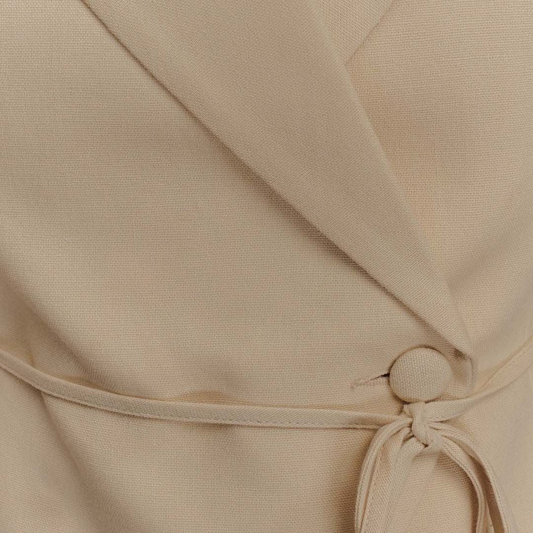 Beige ärmlös kavaj med markerad midja klassiskt slag och knytdetalj framtill i stilren linnemix