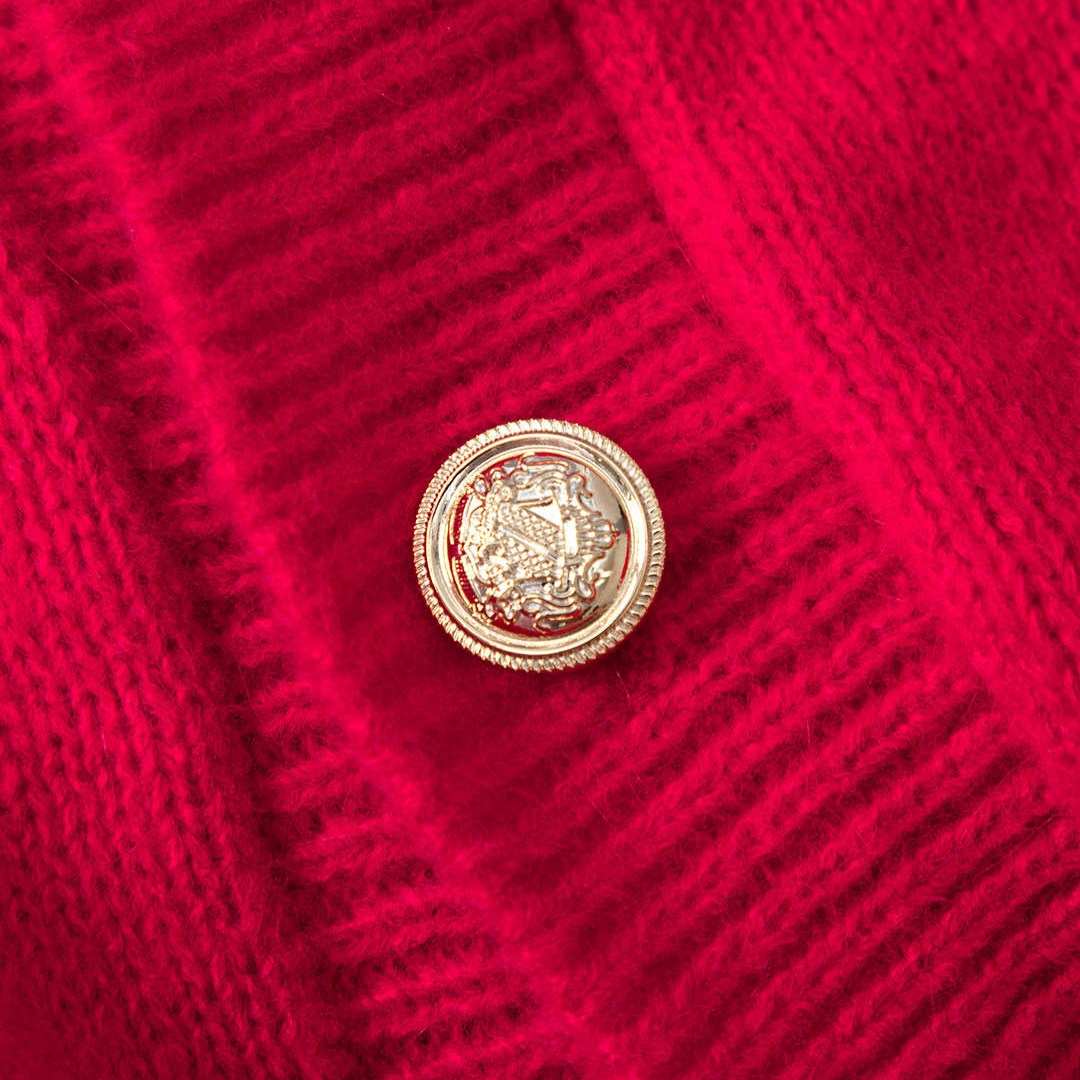 Röd stickad kofta med knappslå och långa ärmar med fuskpälsdetalj