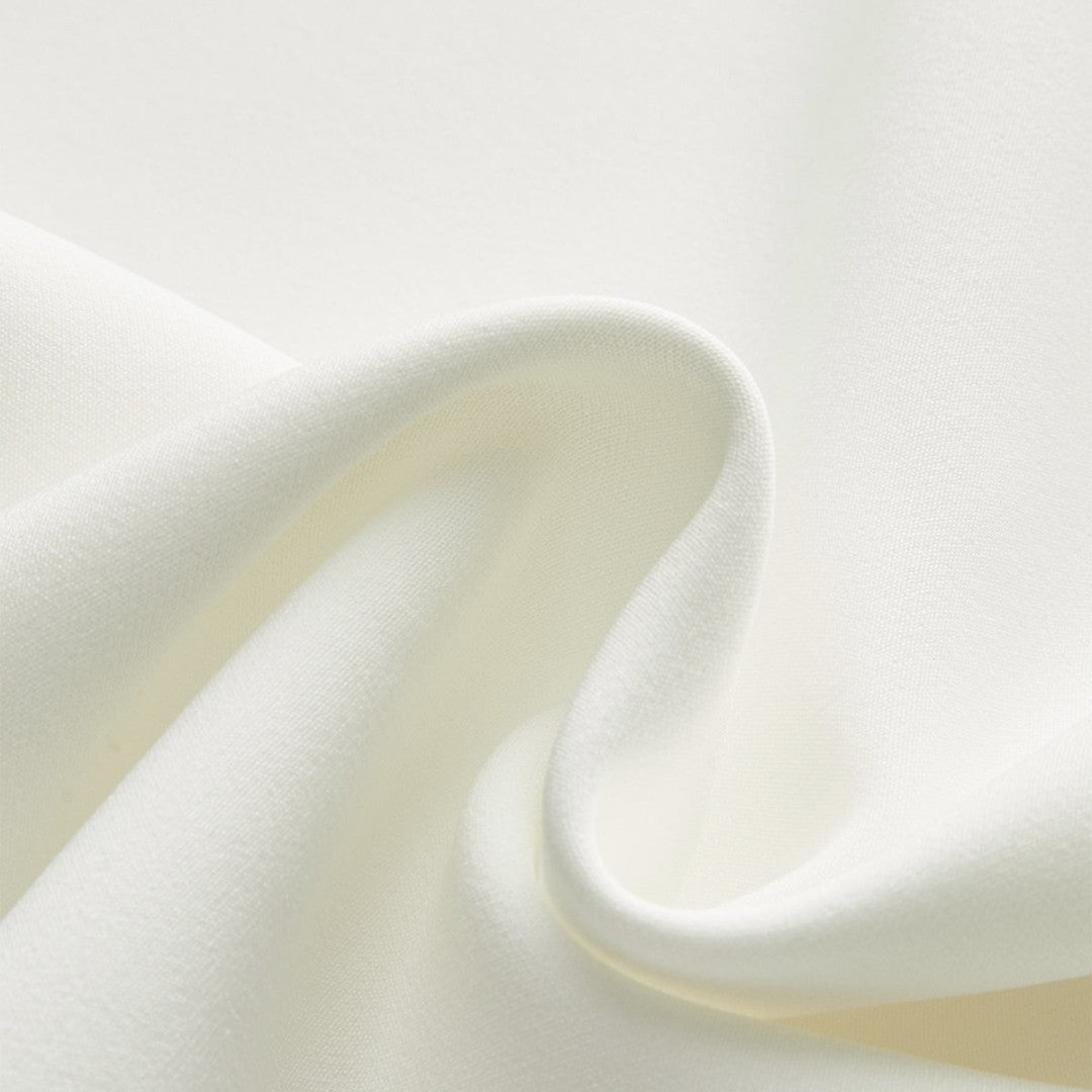 Ärmlös vit väst med asymmetrisk fåll och dekorativa guldknappar