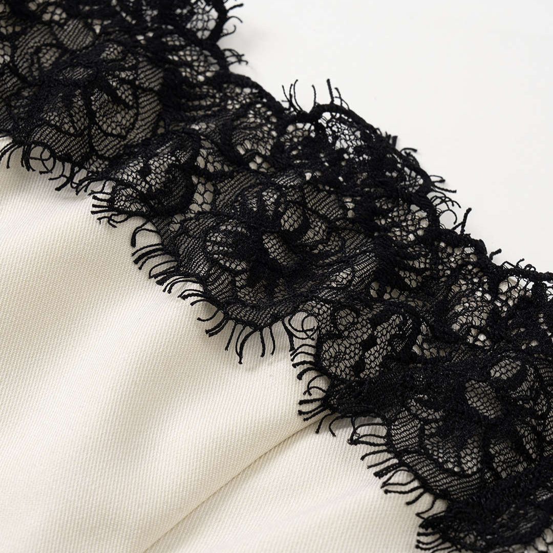 Krämvit midiklänning med svarta spetsdetaljer, smala axelband och figurnära passform