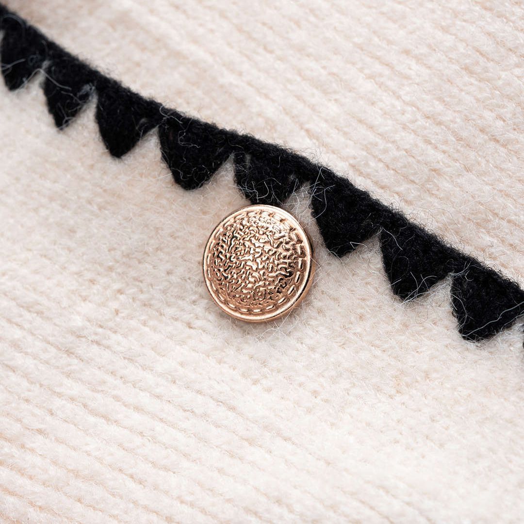 Vit stickad kofta med kontrastkant och dekorativa knappar