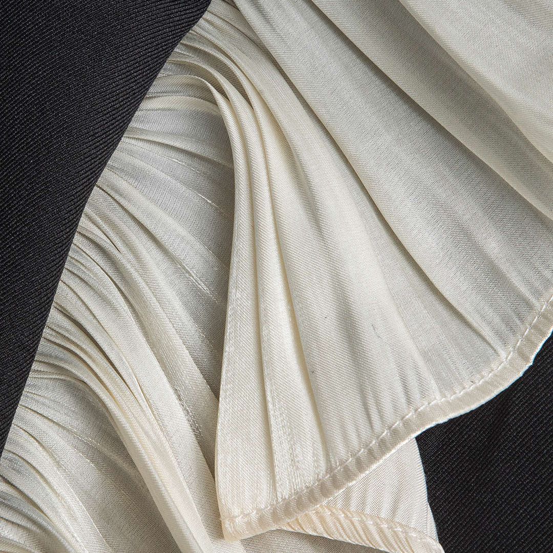 Svart ärmlös kavajväst med plisserade volanger och dekorativt metallspänne