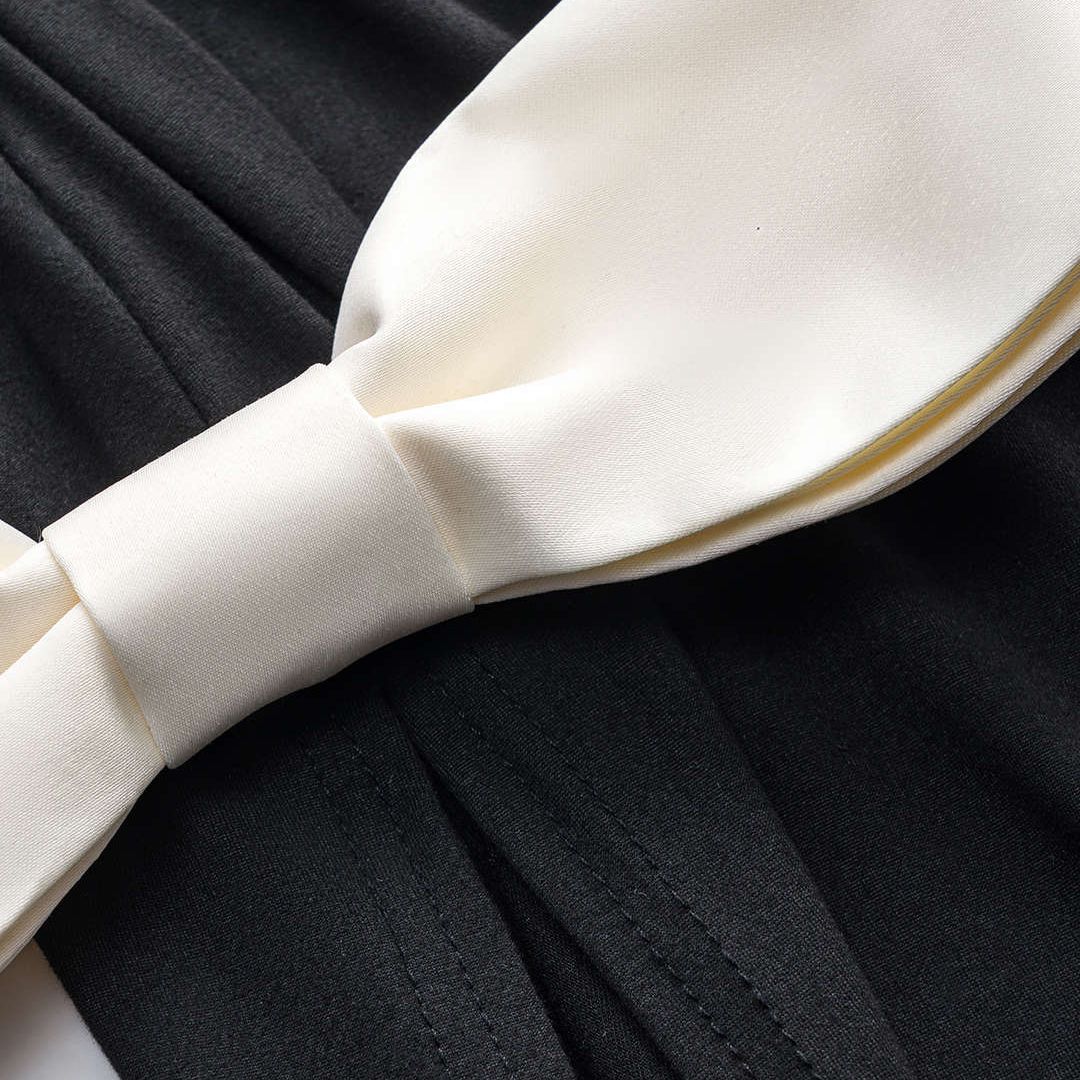 Svart ärmlös långklänning i jersey med figurnära silhuett och kontrasterande sidenrosetter i midjan