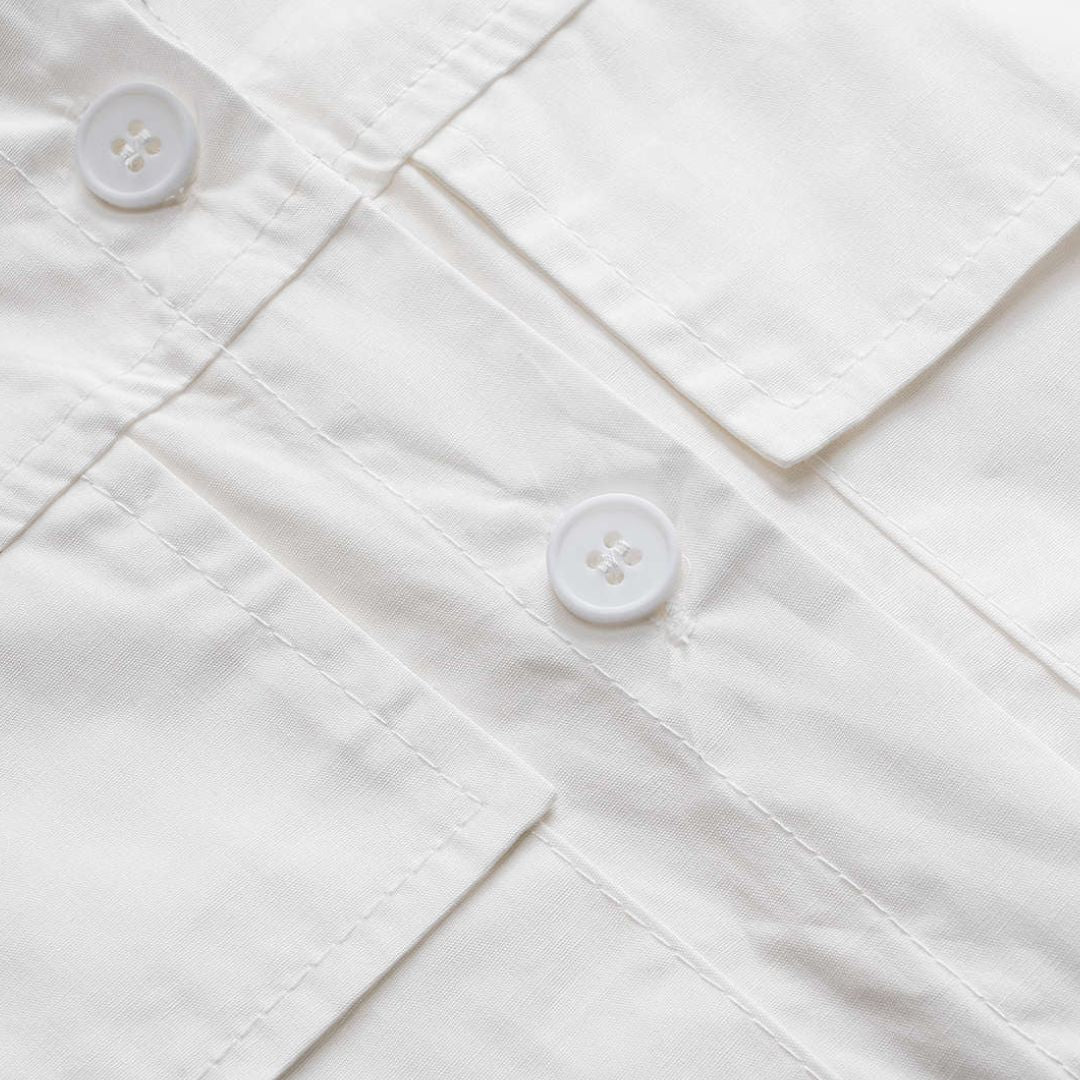 Vit kort skjortblus med stora fickor och dragsko i fållen