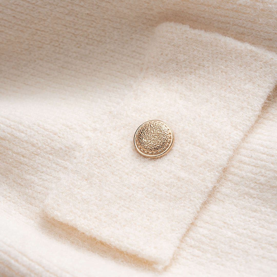 Vit stickad kofta med kontrastkant och dekorativa knappar