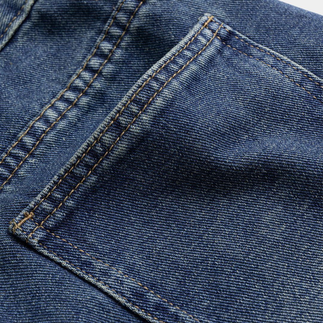 Mörkblå denimbyxa med markerad midja, kjol-liknande överdel och utställda ben