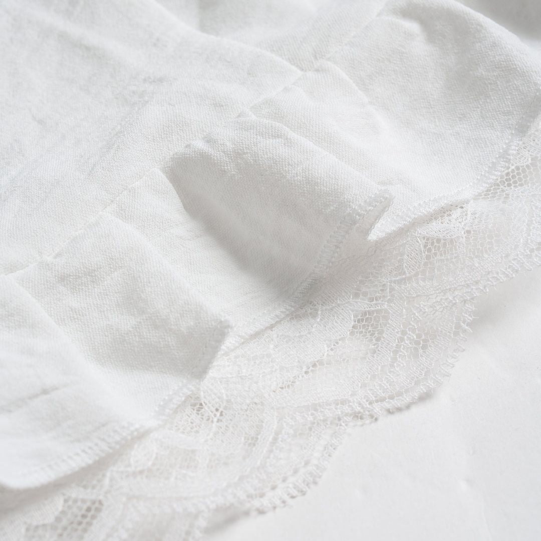 Vit blus med spetskant, korta puffärmar och transparenta knappar