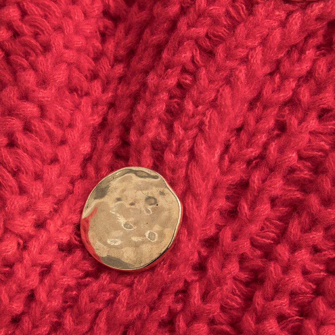 Stickad väst i grov röd maskstickning med dekorativa knappar och framfickor