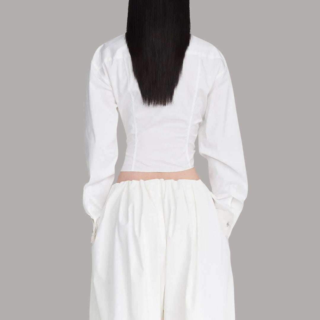 Vit asymmetrisk skjorttopp med markerad midja och industriell spänndetalj