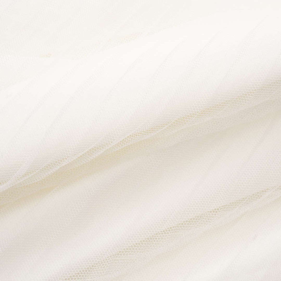 Vit tyllklänning med djup halterneck, volangmidja och plisserad maxikjol