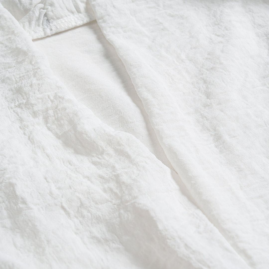 Vit blus med spetskant, korta puffärmar och transparenta knappar