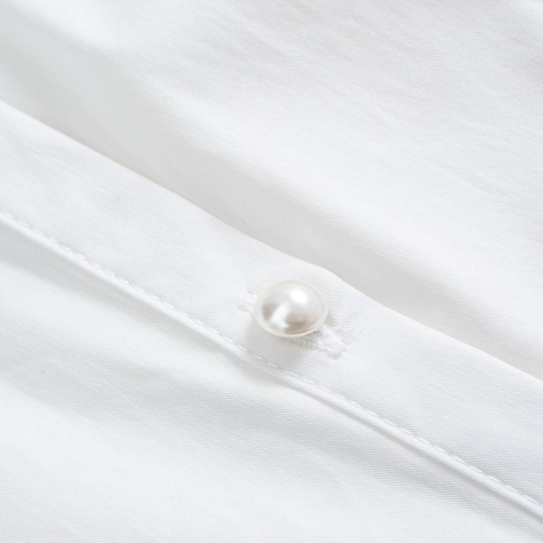 Vit blus med voluminösa draperade ärmar och pärlknappar