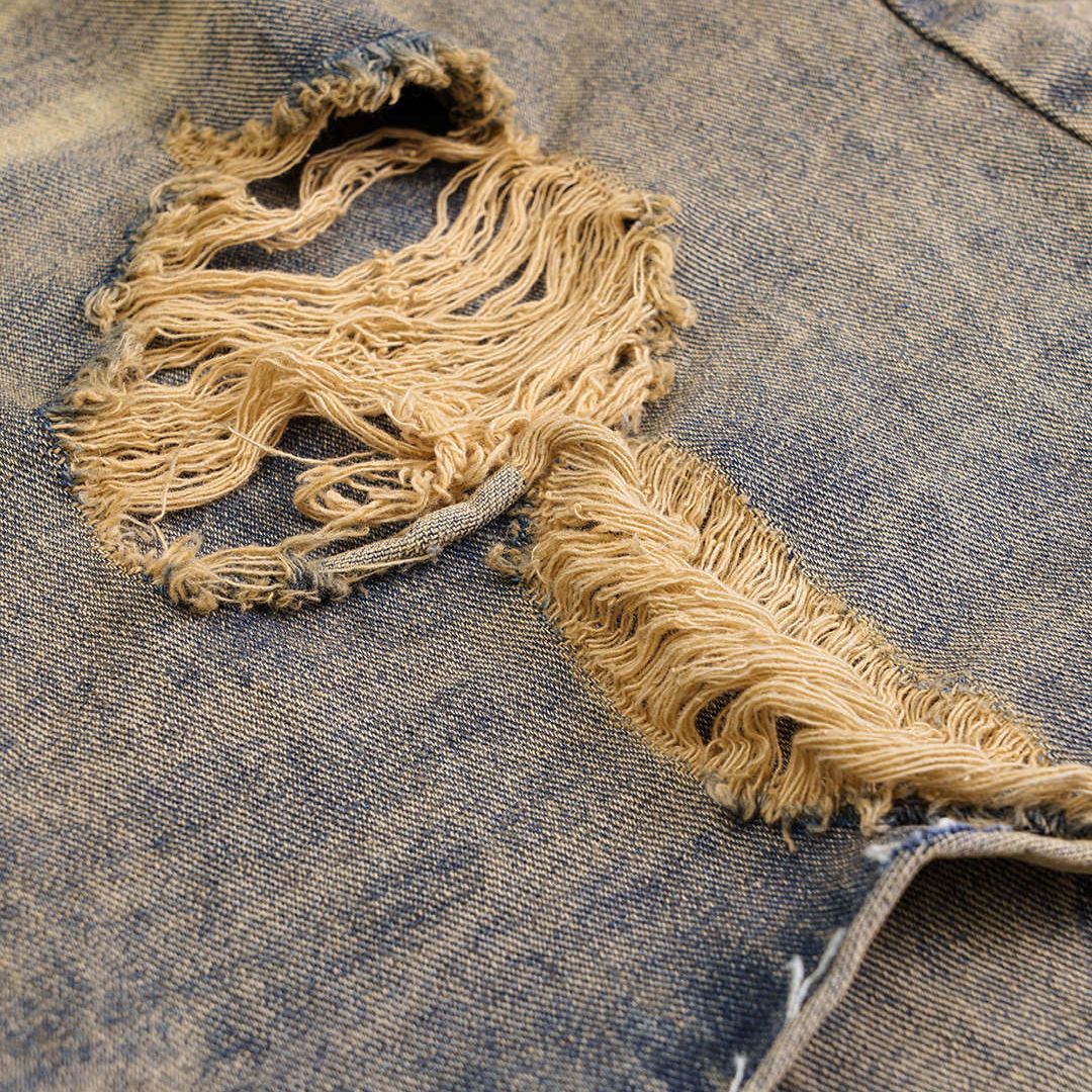 Distressed denimjeans med asymmetriskt shortsöverlägg, rå tvätt och överdrivna slitningar i kraftig bomullsblandning