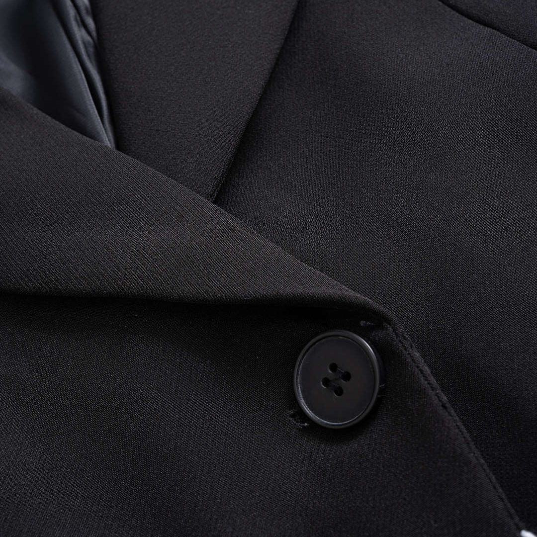 Svart kavajjacka med kontrasterande denimdetaljer och råa kanter i modern tvåtonad design