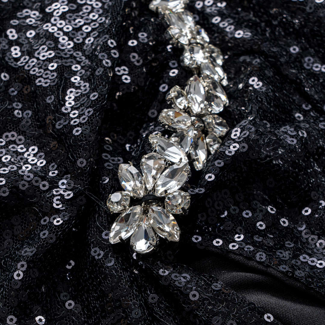 Svart asymmetrisk paljettklänning med dekorativa axelband och kristallapplikationer