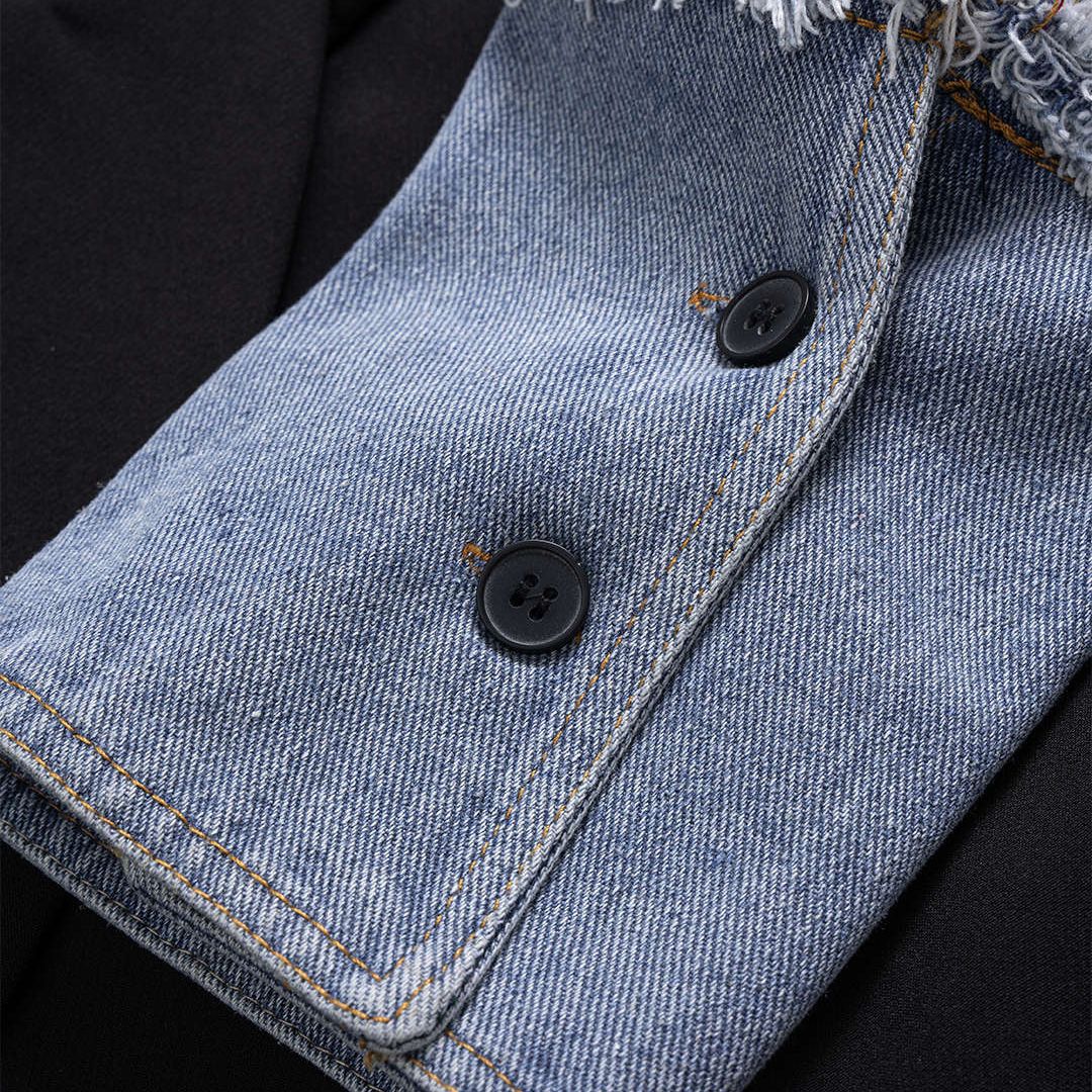 Svart kavajjacka med kontrasterande denimdetaljer och råa kanter i modern tvåtonad design