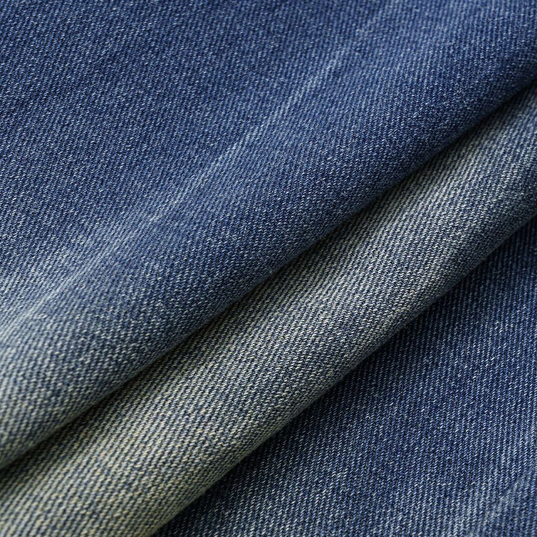 Asymmetriska denimjeans med omlottdesign, blekt färgövergång och vid passform i kraftig bomullsblandning