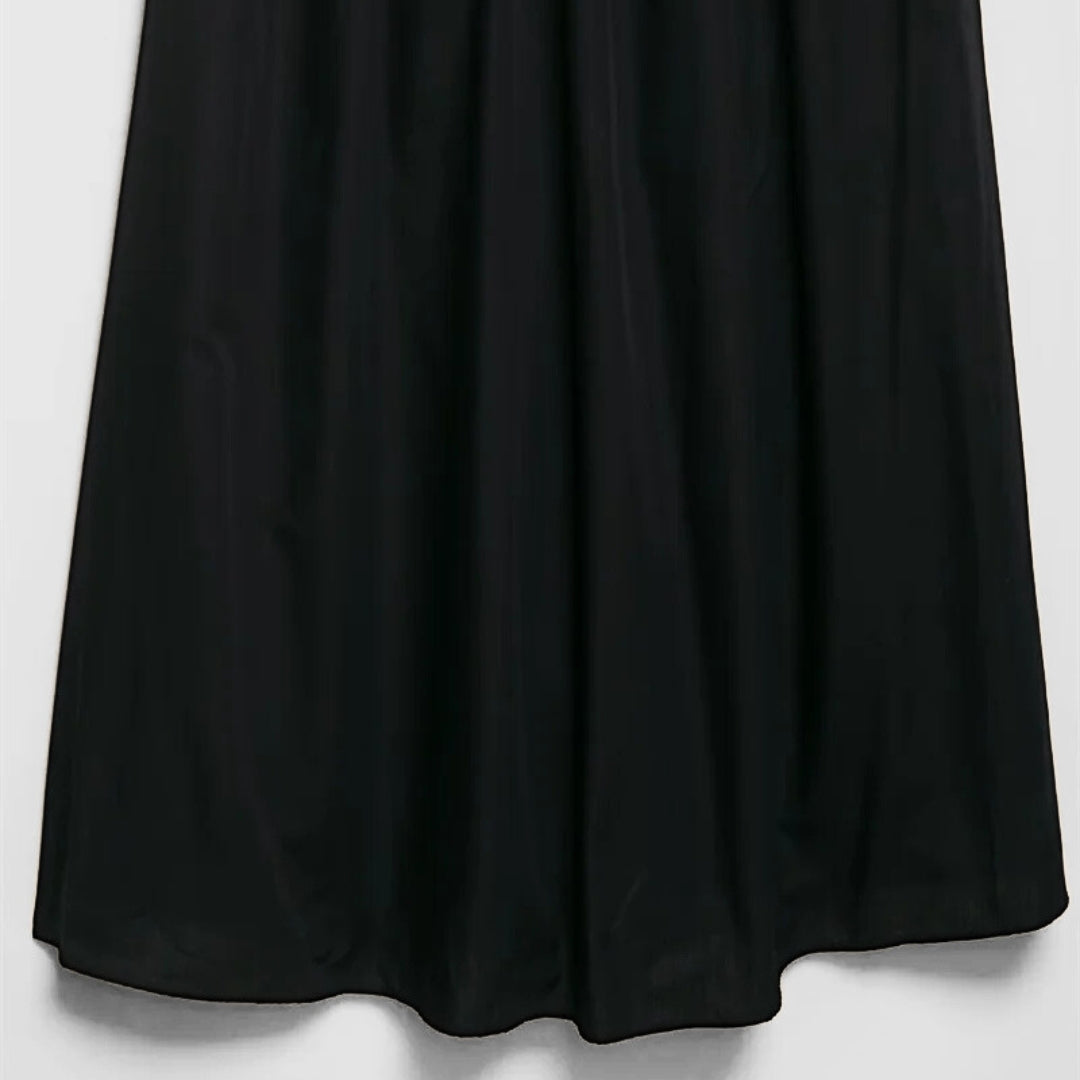 Svart midiklänning med smala axelband, markerad midja och dekorativt bälte